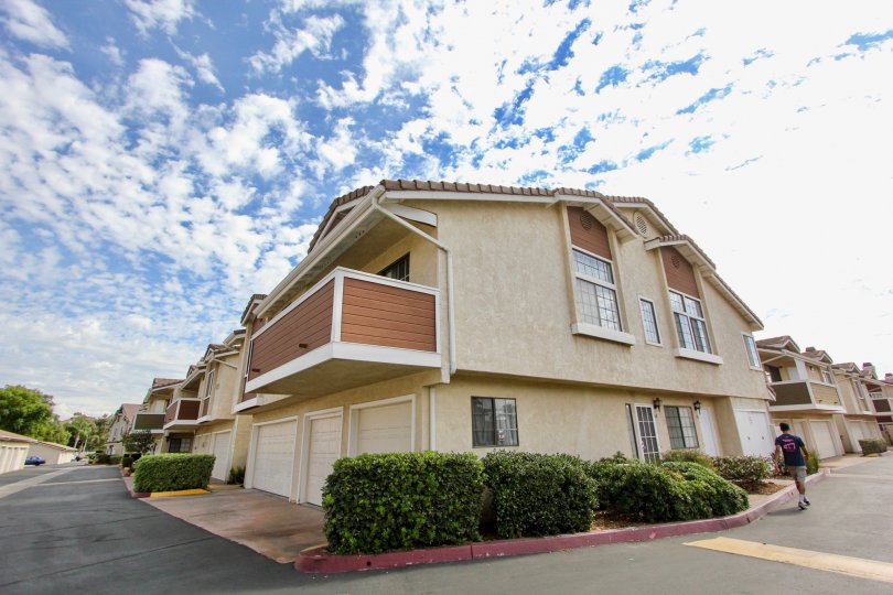 A shrub lined corner intersection and view of a balcony at a home in The Lakes neighborhood in Santee, California