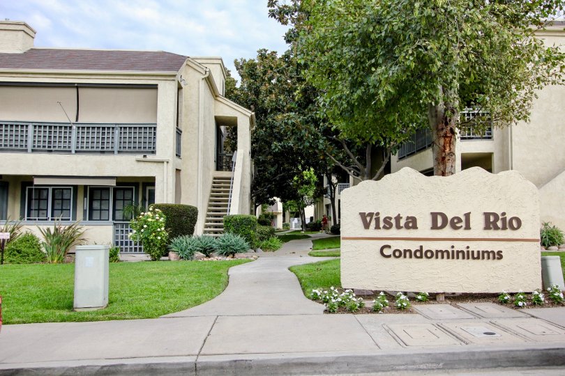 2-story condominium complex with green grass and trees