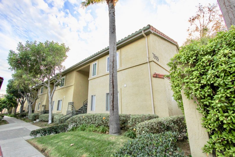 An apartment complex in the Verano community has many trees and bushes out front.