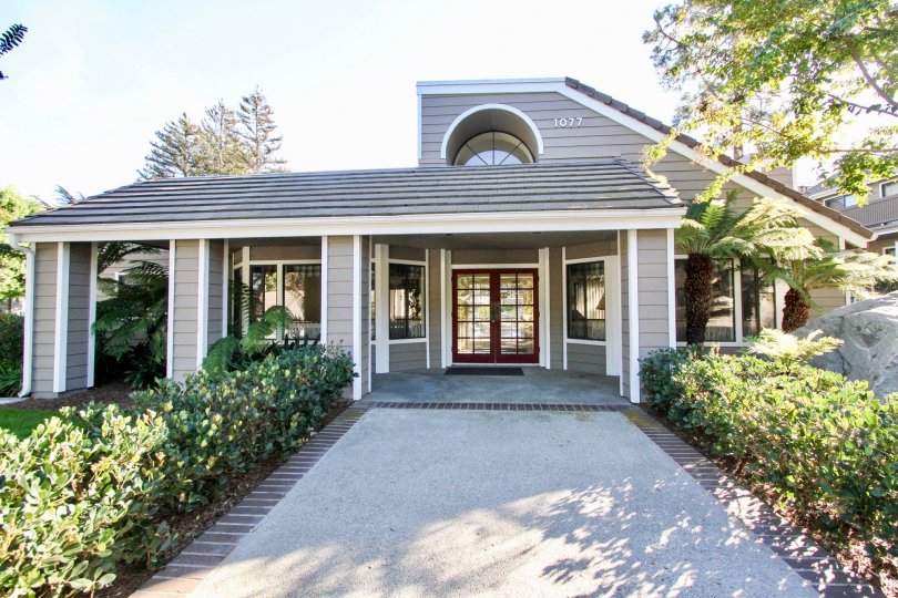 The villa in the Shadowridge Aspens has glass doors and windows with plants on both sides of the pathway