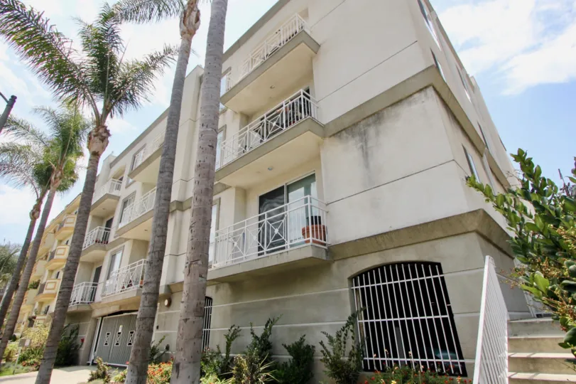 Palm trees and balconies in a mildewed building at 117 S Clark in Beverly Center, California
