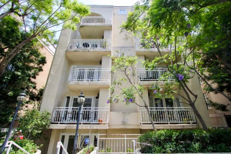 Charming balconies overlook a flowering tree-lined entrance at 146 S Clark in Beverly Center, California