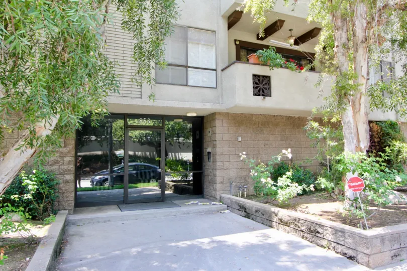 entry of a large house in California with glass doors and plants