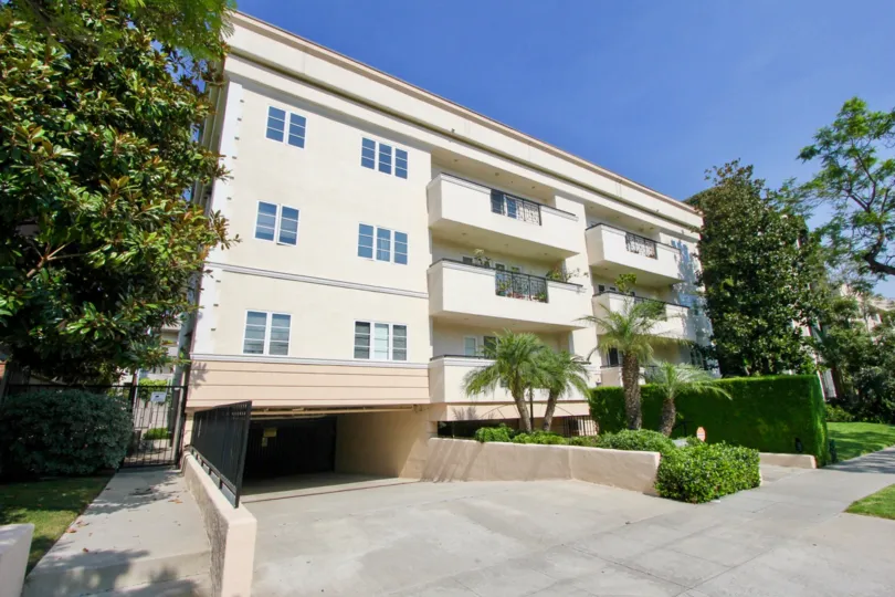 A white house in the Palm Drive Plaza neighborhood with six balconies and tall trees