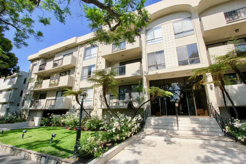 the entry of a building with plants at the side in The Beverly Palm Condominiums