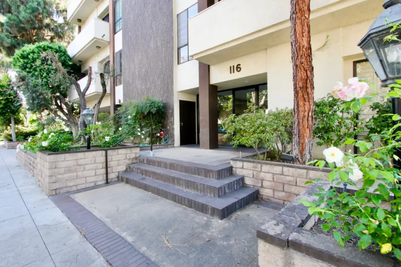 The front of a building with trees, grass and flowers