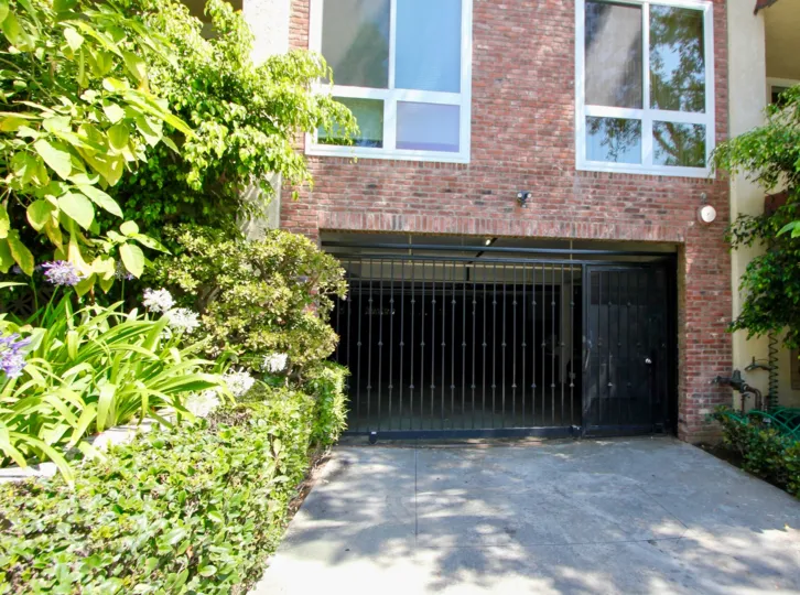 A red brick house at 11918 Kiowa with two large windows and green plants