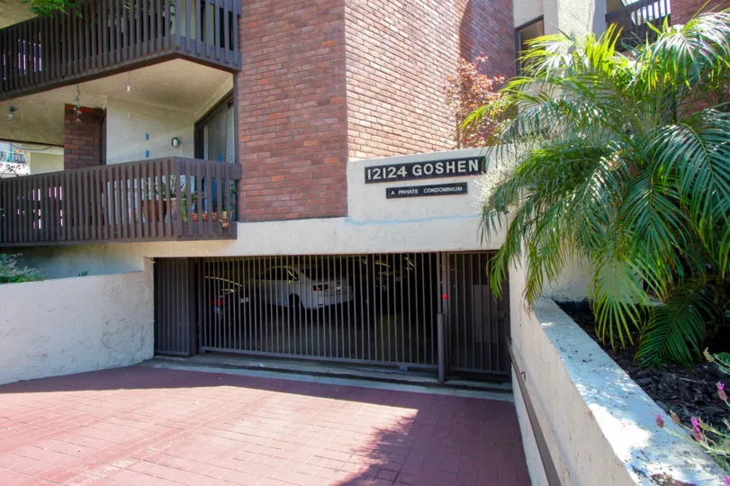 Closed and gated parking garage entrance for an apartment building with balconies visible above and to the left.