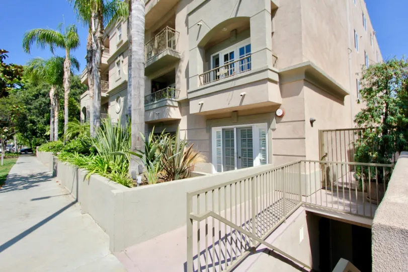 A tan building in the Brentwood Darlington community with palm trees and a balcony