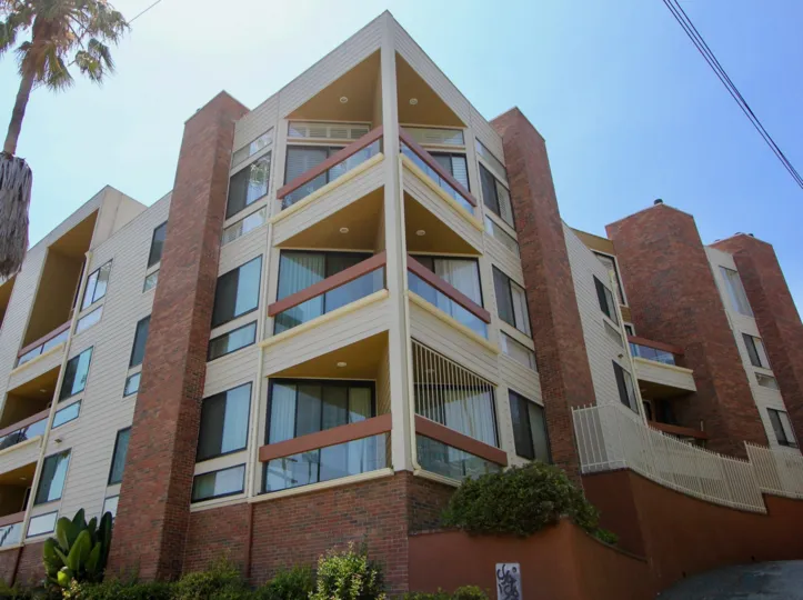 Corner of building at Bundy Brentana with sliding glass doors leading to corner patios and brick colums
