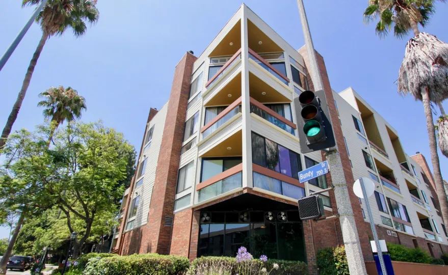 A tall red brick building in the Bundy Brentana community with multiple balconies and palm trees