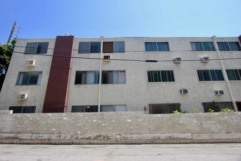 A plain apartment building with a parking lot in Casa Real