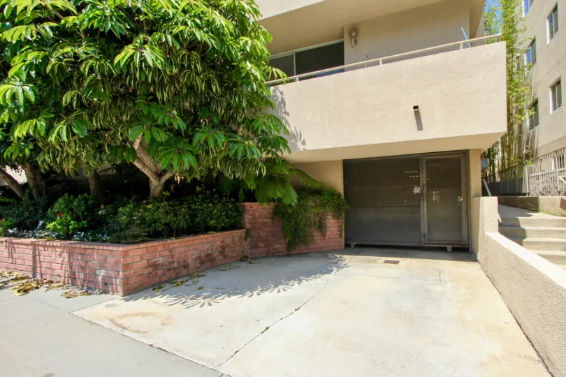 A gated entrance underneath a balcony next to a tree at Concept 84.