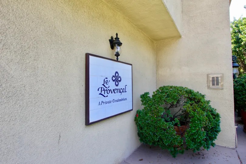 A beige-colored building with stucco walls and a green bush in Le Provencal