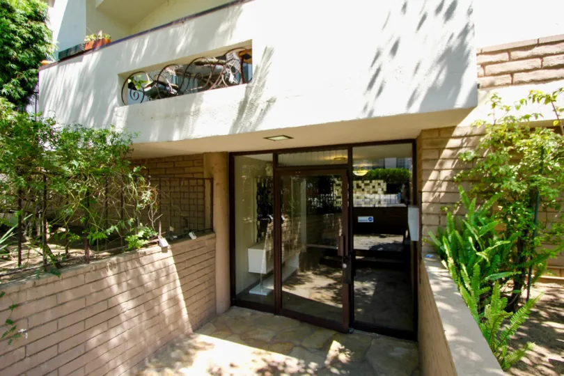 Mayfield Plaza glass door entrance with stone walkway and brick walls and landscaping