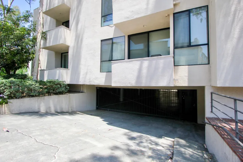 Trees and a gated parking area under the balconies at VIP Barrington in Brentwood, California