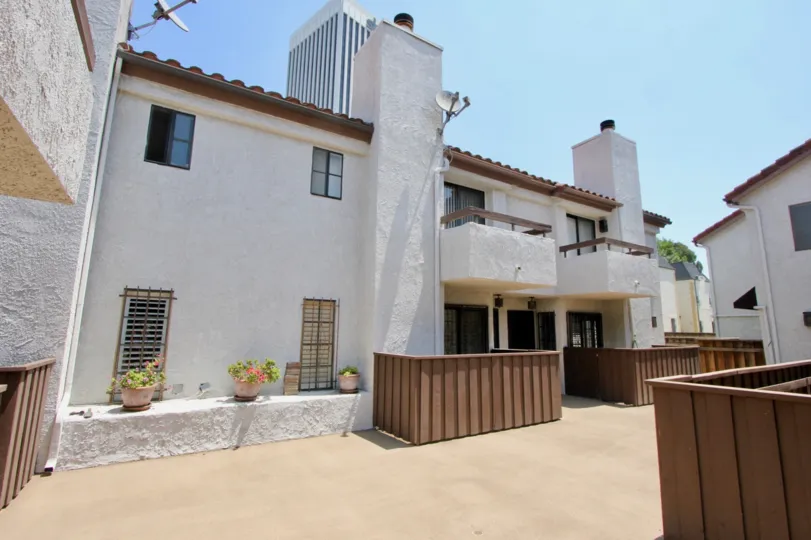 this is a lovely building with brown fencing and it is decorated with some potted flowers