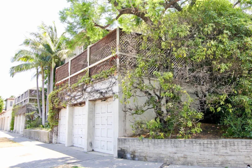 Personal garages at II Borghese with trees and vines, large sidewalk space.