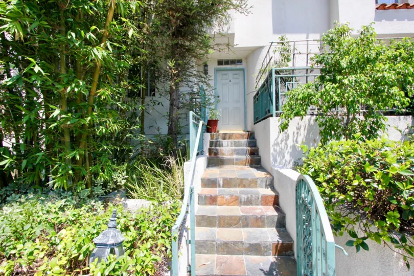 Charming stairway lined with landscaping and blue-trimmed railings of the Norton Townhouse in Hancock Park California.