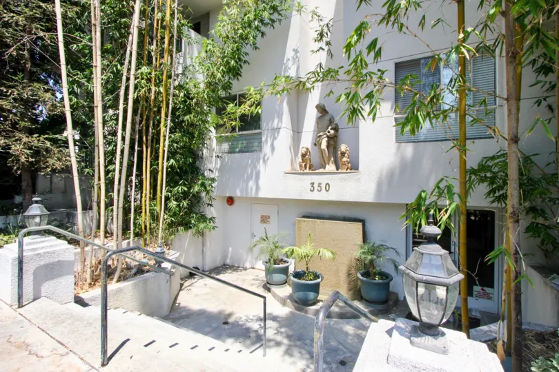 Patio of a white building featuring a statue and potted plants in the Norton Townhouse community of Hancock Park, California.