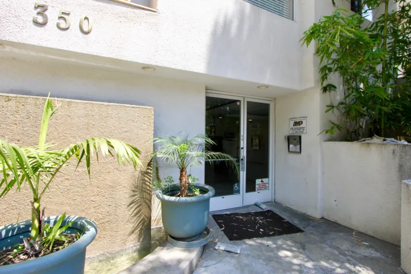 Norton Townhouse in hancock park city, California entrance view with beautiful glass door and light blue colored plant vases and lots of greenery.