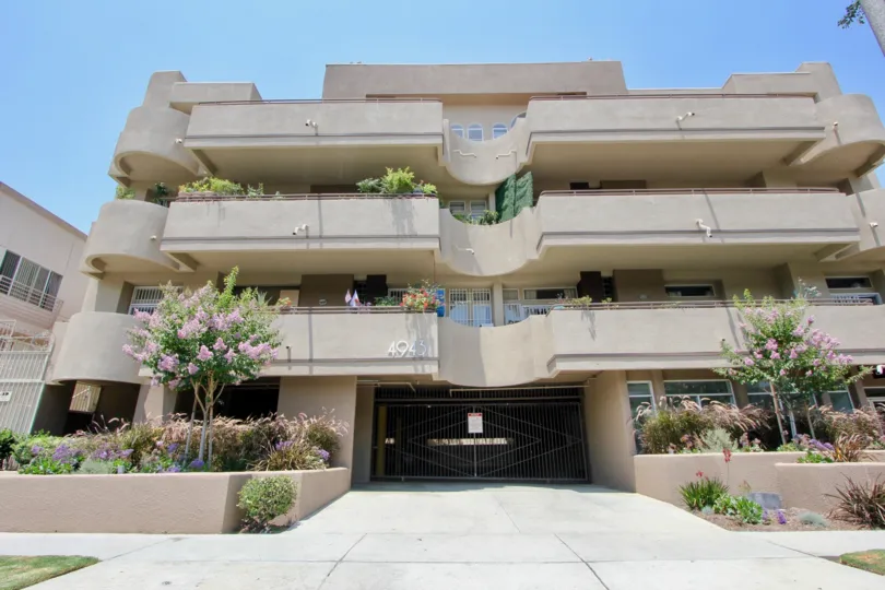 Building with modern touches in design with large balconies and flower beds with pink flowers