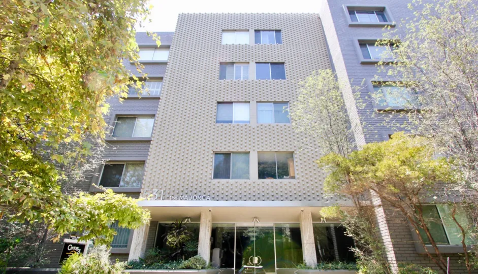 A beautiful sky high well construct building which have white colour and shiny bright glass window. Lots of green trees enhance its beauty. A sunny bright day give it an amazing look.