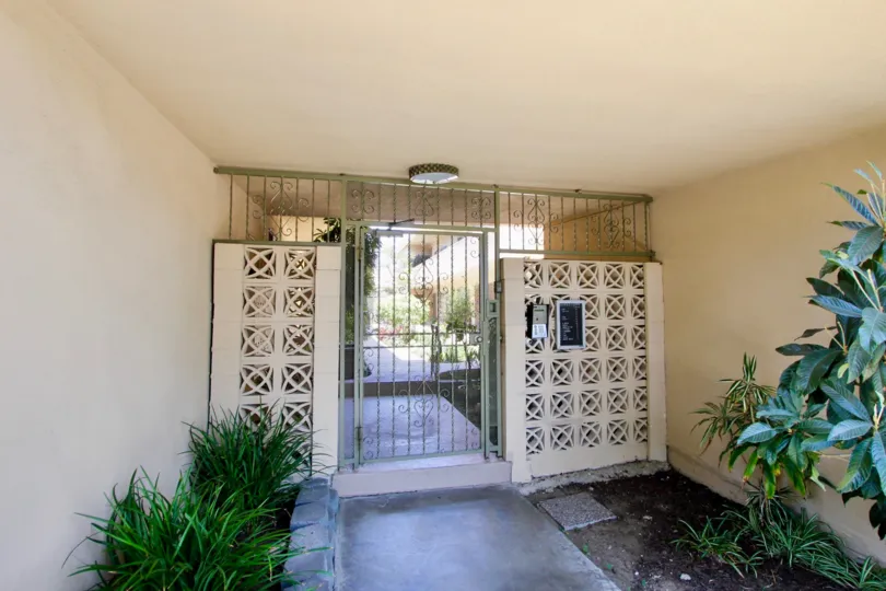 THE FRONT GATE WITH CLOSED ONE AND SOME PLANTS ALSO AVAILABLE AND A LAMP AT THE WALL AT THE MORNING SIGHT