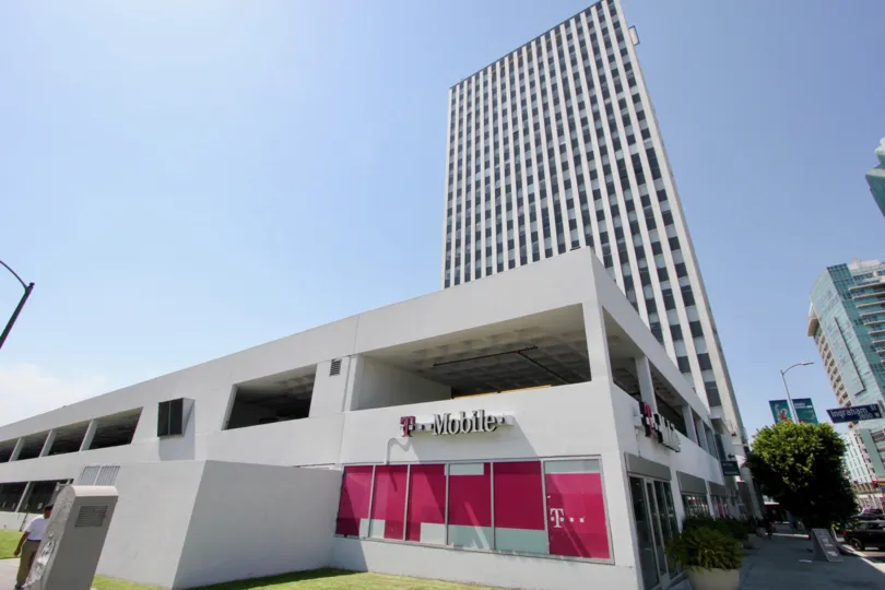A corner location of a T-Mobile store with a high rise building in the background