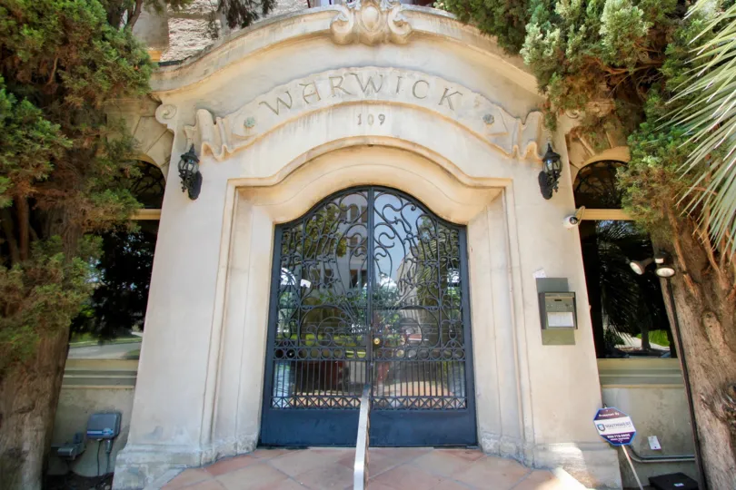 An entrance old door of The Warwick, hancock park, California with glass and grill door. Beautiful green tries looks good both sides.