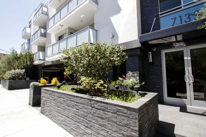 Hawthorn in Hollywood entrance has raised planters made of stacked stone full of lush greenery