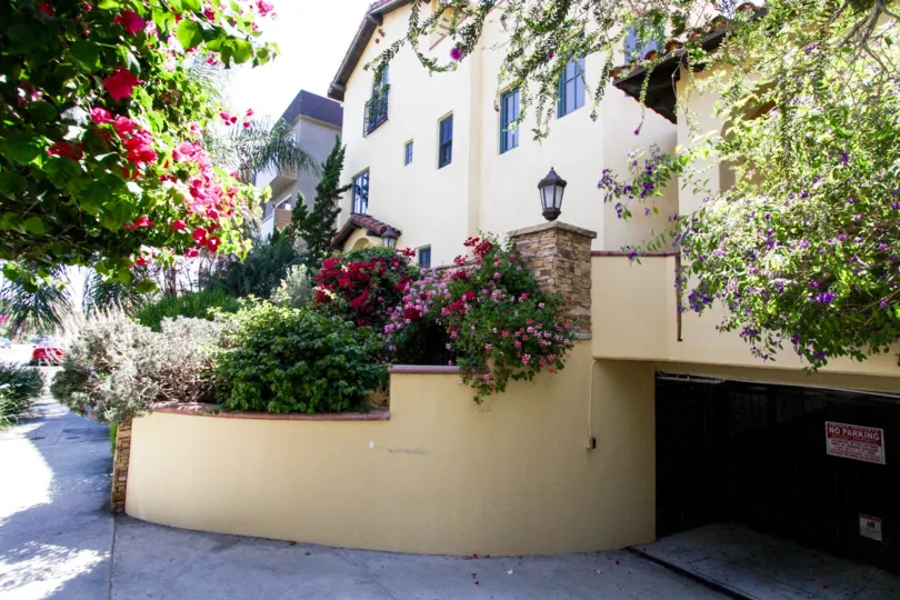 A rounded stucco planters lead cars down to the gated parking garage for La Serenata