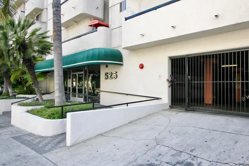 A Berendo Tower entrance by parking garage entrance gate with palm trees