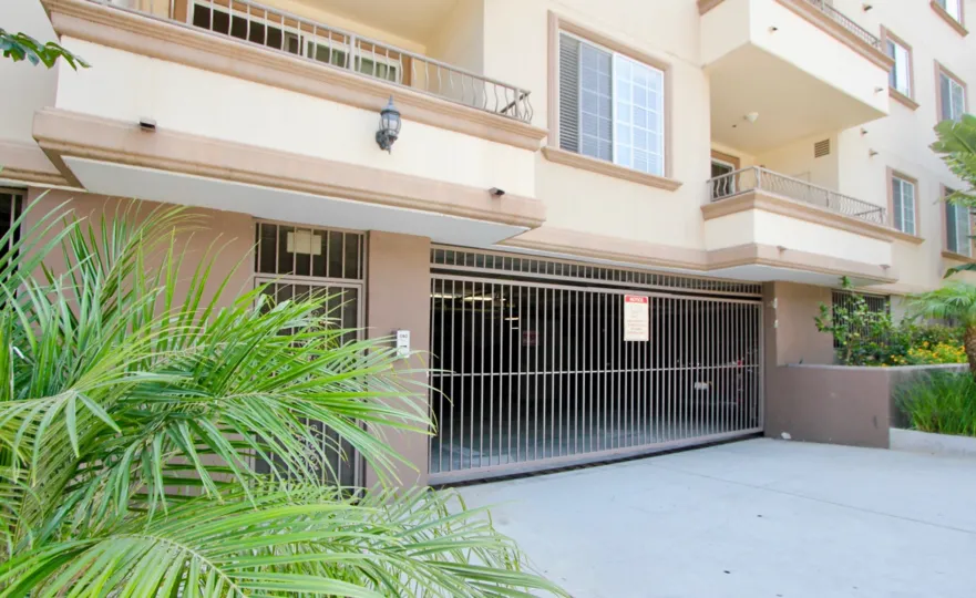 Parking garage entrance gate at Gramercy Homes with landscaping shrubs.