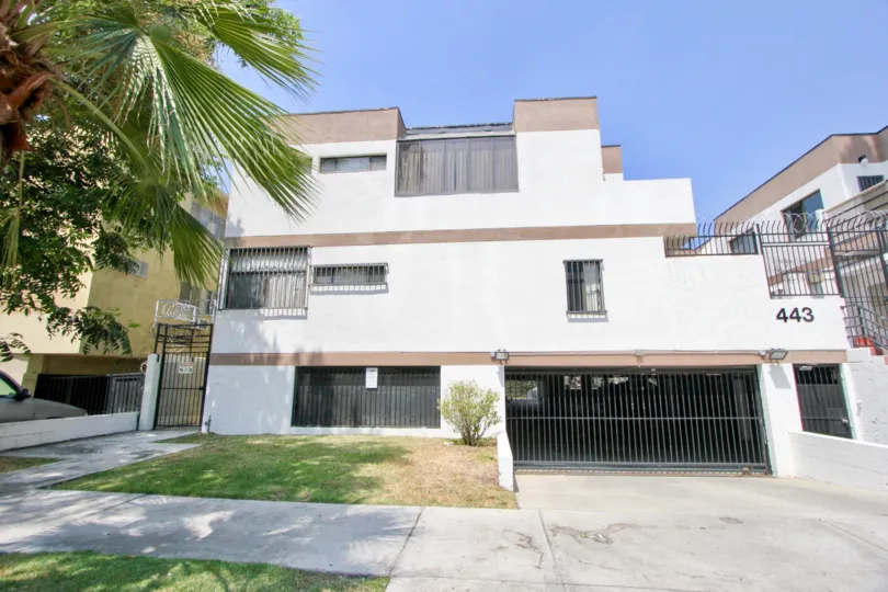 Large house with a huge porton of black bars and a patio that only has a single shrub burned by the sun