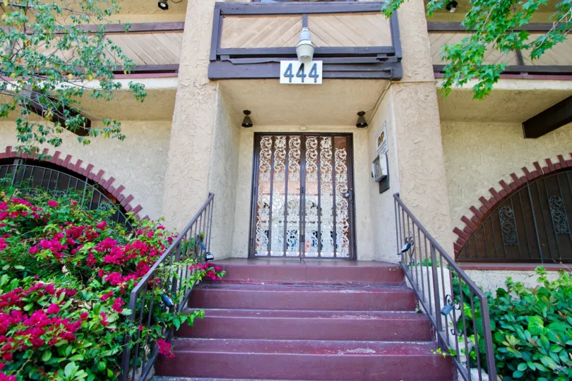 Hancock townhome no. 444 in Koreatown with ornate door and steps, flowers blooming to the left.
