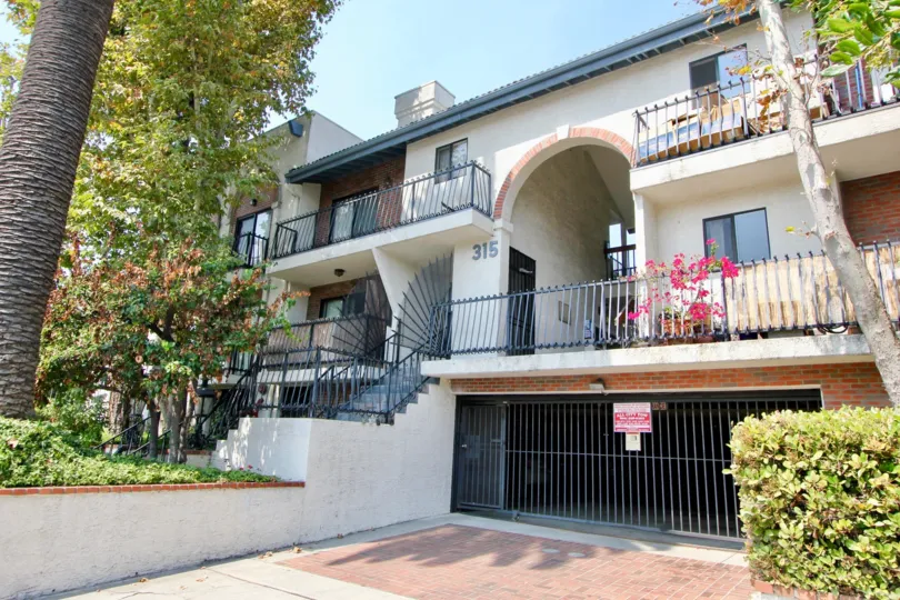 A sunny day at Harvard Gardens Apartments with trees and balcony views