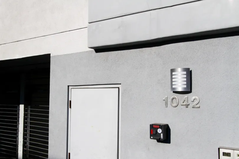Metal address numbers attached to the stucco side of the Kingsley Manor building