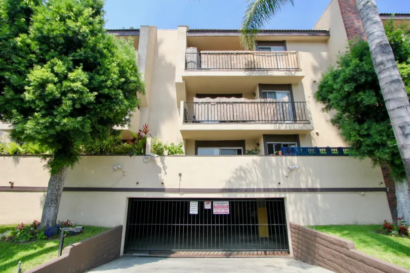 Condominium building showing entrance to a garage and two covered balconies and a tree in front of the building