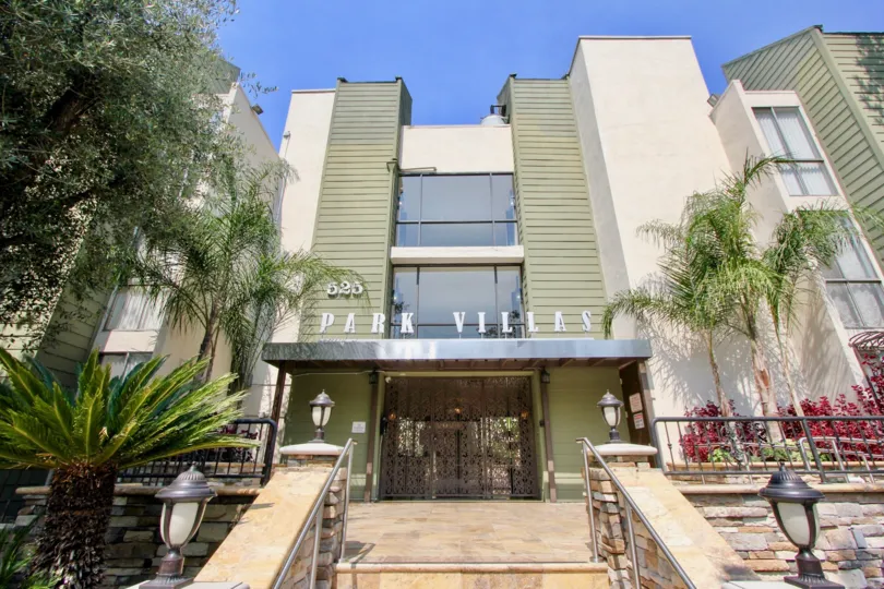 Entrance to Park Villas in sunny Koreatown, CA with palm trees and flowers.