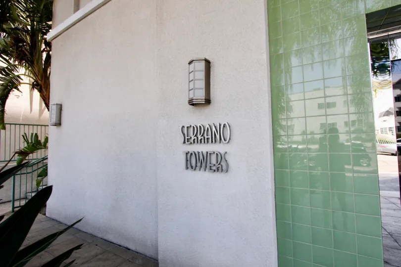 The entrance sign and Serrano Towers building in the shade in Koreatown