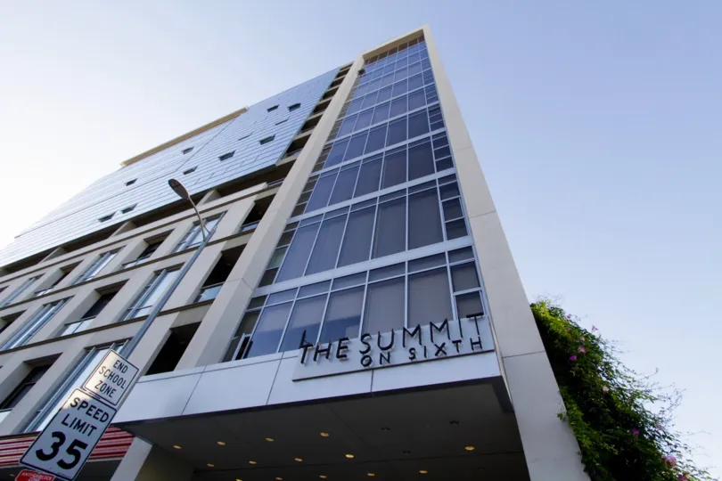 The entrance to The Summit on Sixth shows a tall building with walls of glass
