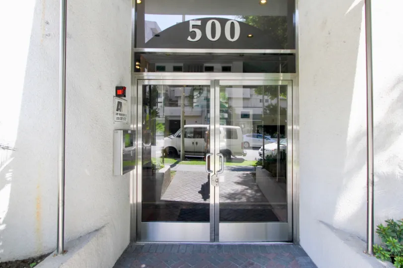 Front entrance to Wellington Grande with large glass doors and call box.
