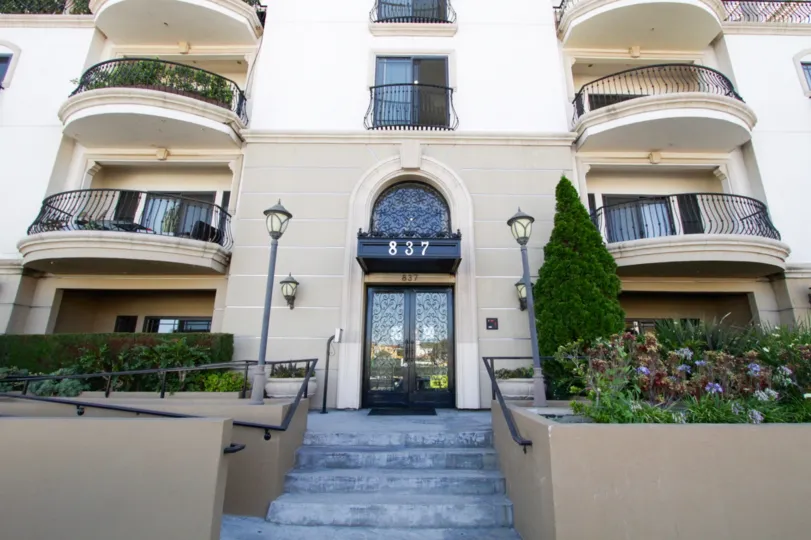 The entrance to Wilshire Park Villa is up a flight of stairs leading to a ornate metal door with glass