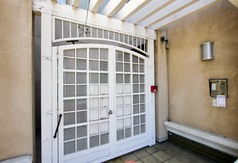 An entrance secure with white screen door, security camera, and call box in the Wilton Plaza community of Koreatown, California.