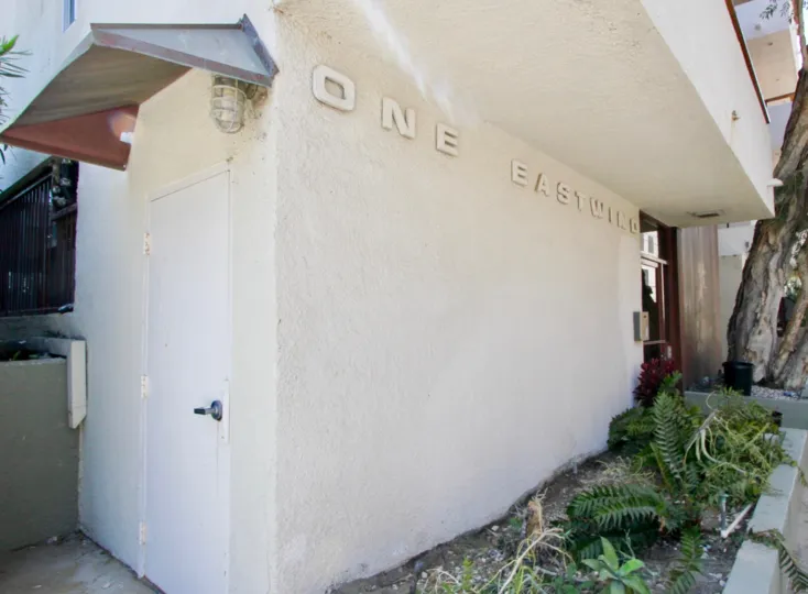 1 Eastwind, marina del rey, California is A beautiful entrance with pretty good gate and lots of greenery including plants and trees. Colourfull flowers are adding life in the picture.
