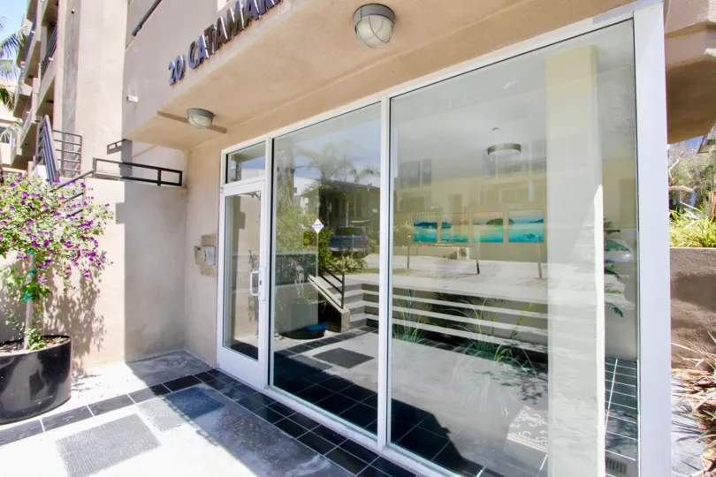 A close view of 20 Catamaran, a building with a tiled walkway and potted pots out front.