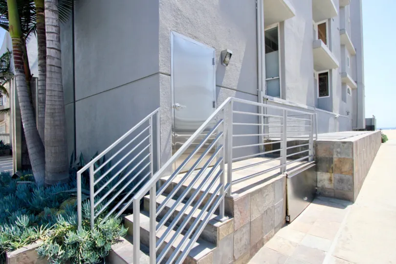 A stepped entrance to 6 Fleet, Marina del Rey, California with palm trees and other tropical plants.