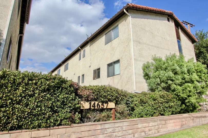A view of the 14657 Nordhoff St community sign with large dormatory buildings in the background