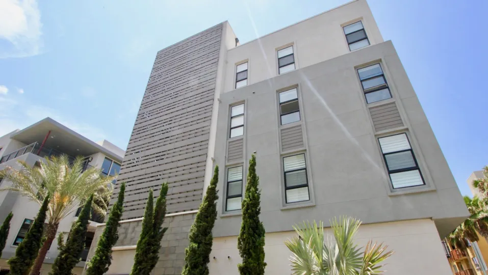a grey building in cleo with trees in the front in a sunny day